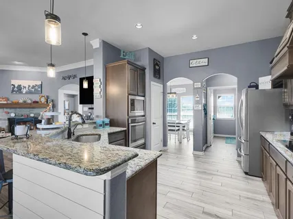 a kitchen with stainless steel appliances granite countertop a refrigerator a stove and a sink