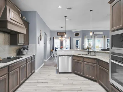 a kitchen with stainless steel appliances granite countertop a sink a stove and cabinets