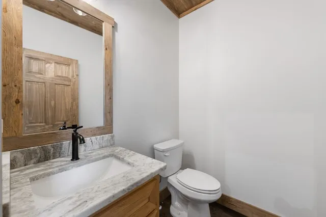 a bathroom with a granite countertop toilet a mirror and a sink