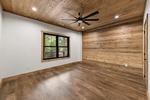 an empty room with wooden floor ceiling fan and windows