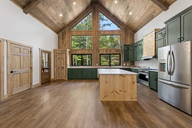 a kitchen with stainless steel appliances granite countertop a refrigerator a stove top oven a sink and a large window