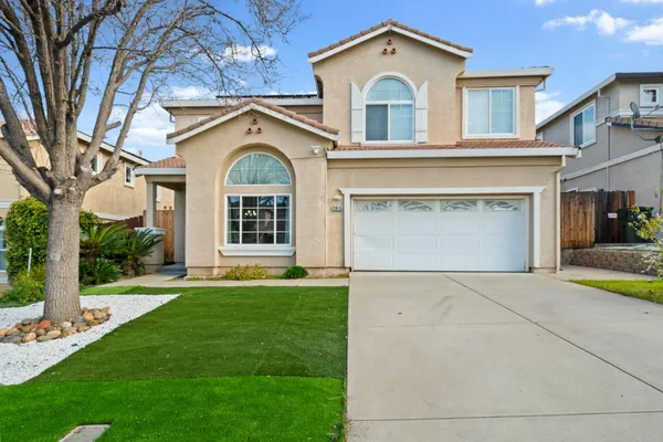 a view of a white house with a large windows and a yard with plants and large tree