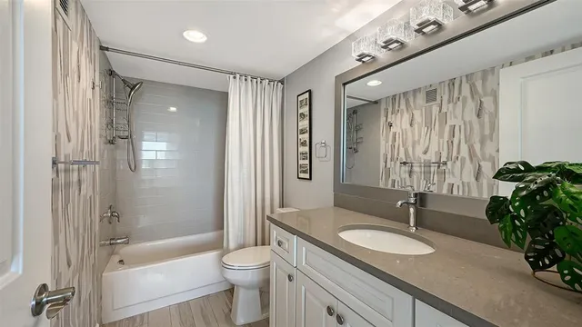 a bathroom with a granite countertop sink toilet a mirror a vanity and shower
