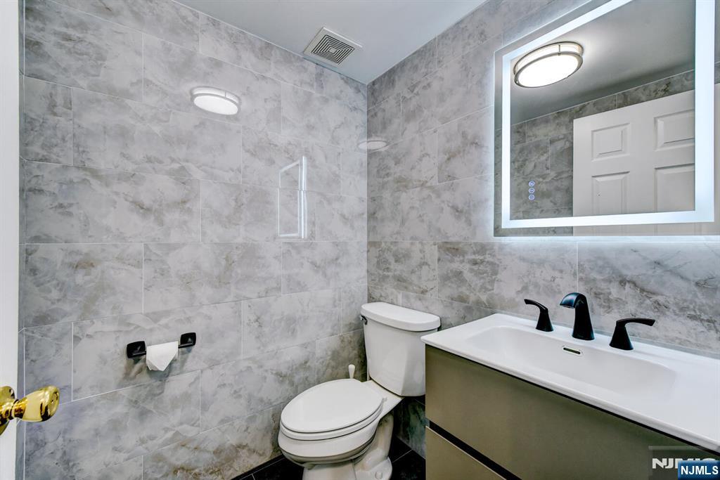 6 Hansen Place, Unit 6 Wayne, NJ 07470 - Photo 26 of 49 a bathroom with a granite countertop sink a toilet and a mirror