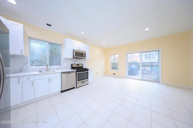 a large kitchen with granite countertop a sink and white cabinets