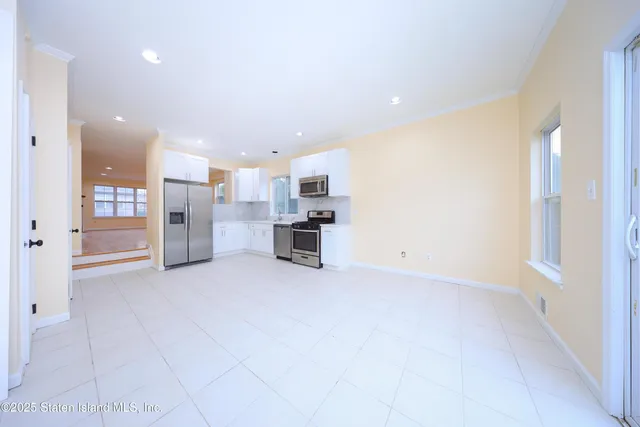 a view of kitchen with refrigerator and white cabinets