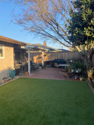 a view of a patio with table and chairs potted plants and large tree