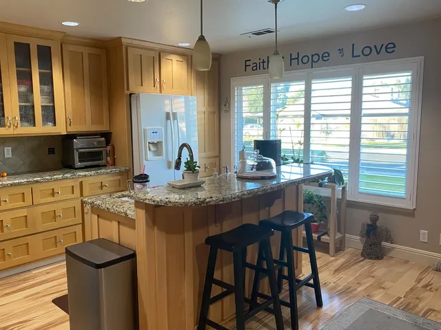 a kitchen with stainless steel appliances granite countertop sink stove and white cabinets with wooden floor