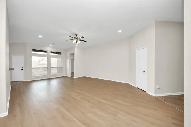 a view of an empty room with a window and wooden floor