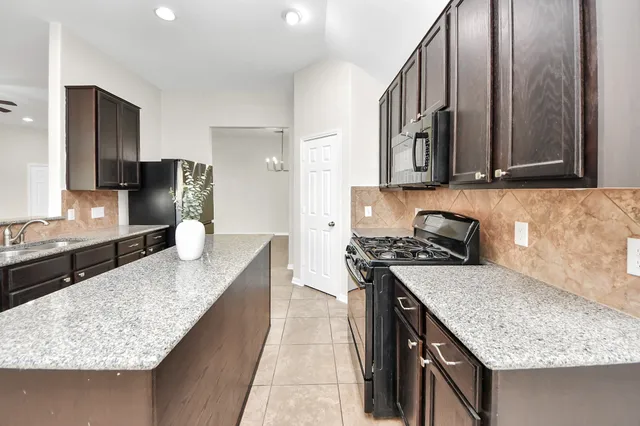 a kitchen with stainless steel appliances granite countertop a sink stove and refrigerator