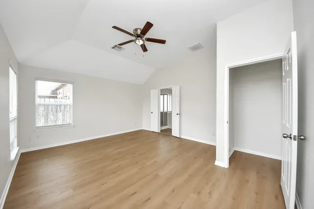a view of empty room with wooden floor and fan