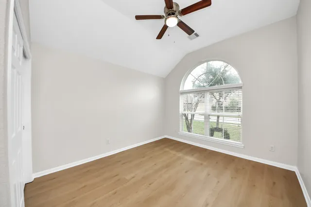 an empty room with a window and a ceiling fan