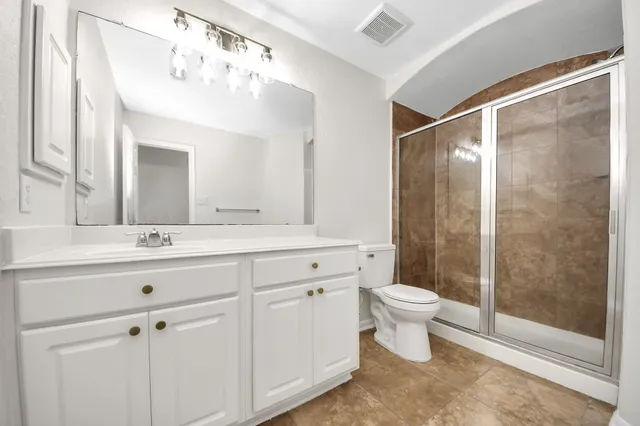 a bathroom with a sink a toilet a mirror and shower