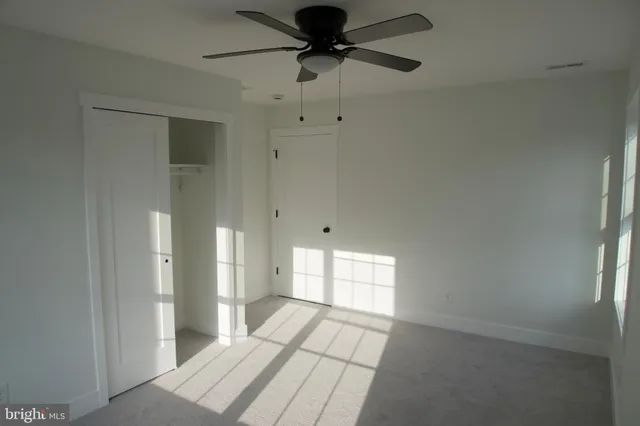 a view of a livingroom with a chandelier fan and windows