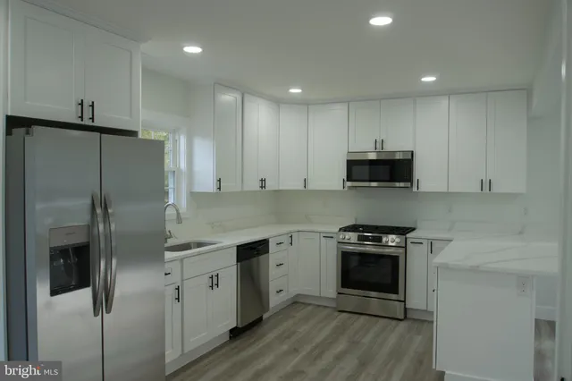 a kitchen with stainless steel appliances a refrigerator a stove a microwave and white cabinets