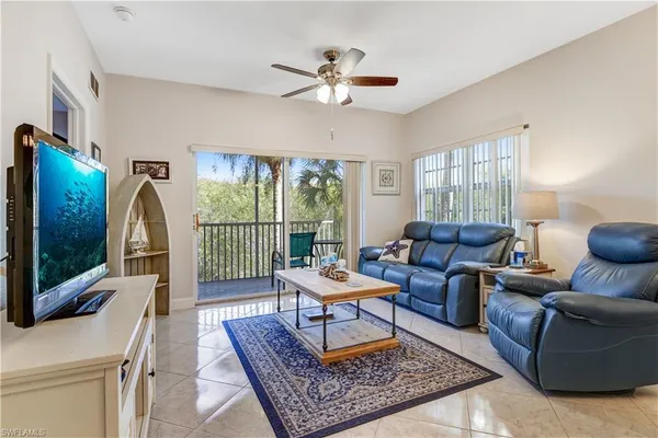 a living room with furniture a flat screen tv and a floor to ceiling window