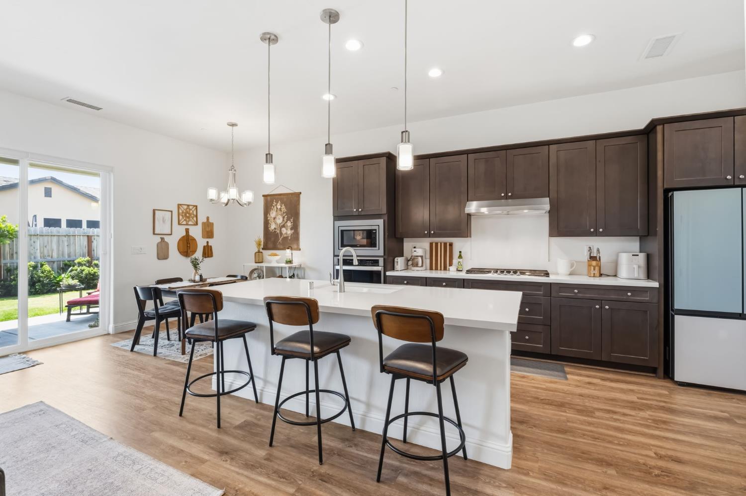 2100 Azalea Street Kingsburg, CA 93631 - Photo 3 of 54 a kitchen with stainless steel appliances granite countertop a refrigerator a stove top oven a sink dishwasher a dining table and chairs with wooden floor