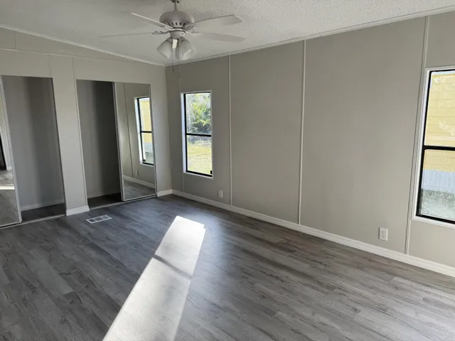 an empty room with wooden floor and windows