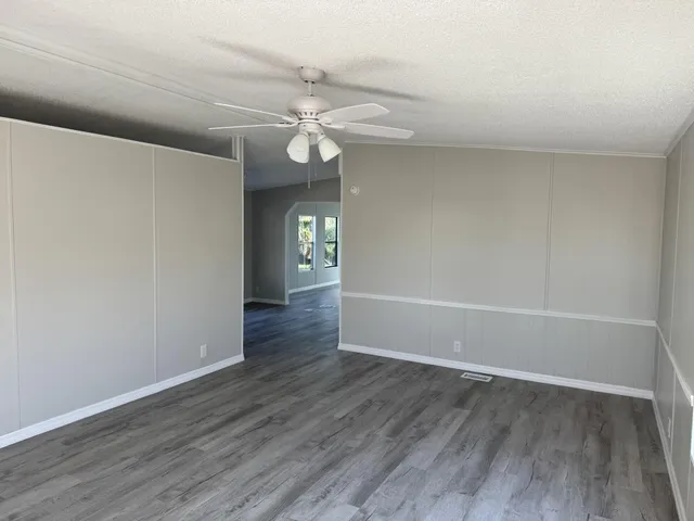 an empty room with wooden floor fan and window