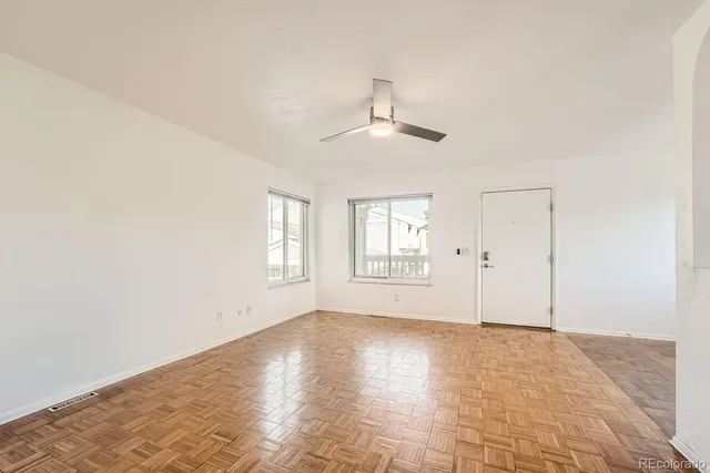 a view of empty room with wooden floor and ceiling fan