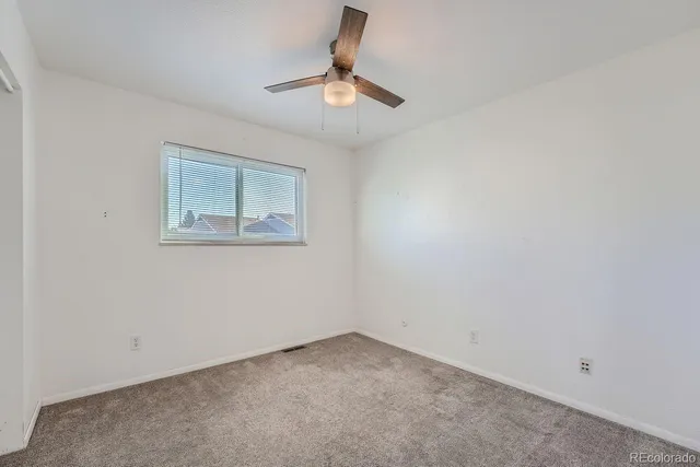 an empty room with a ceiling fan and window
