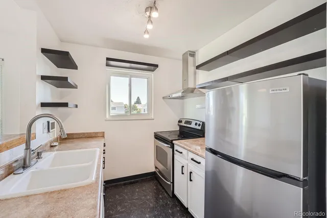 a kitchen with stainless steel appliances granite countertop a sink a refrigerator and a stove