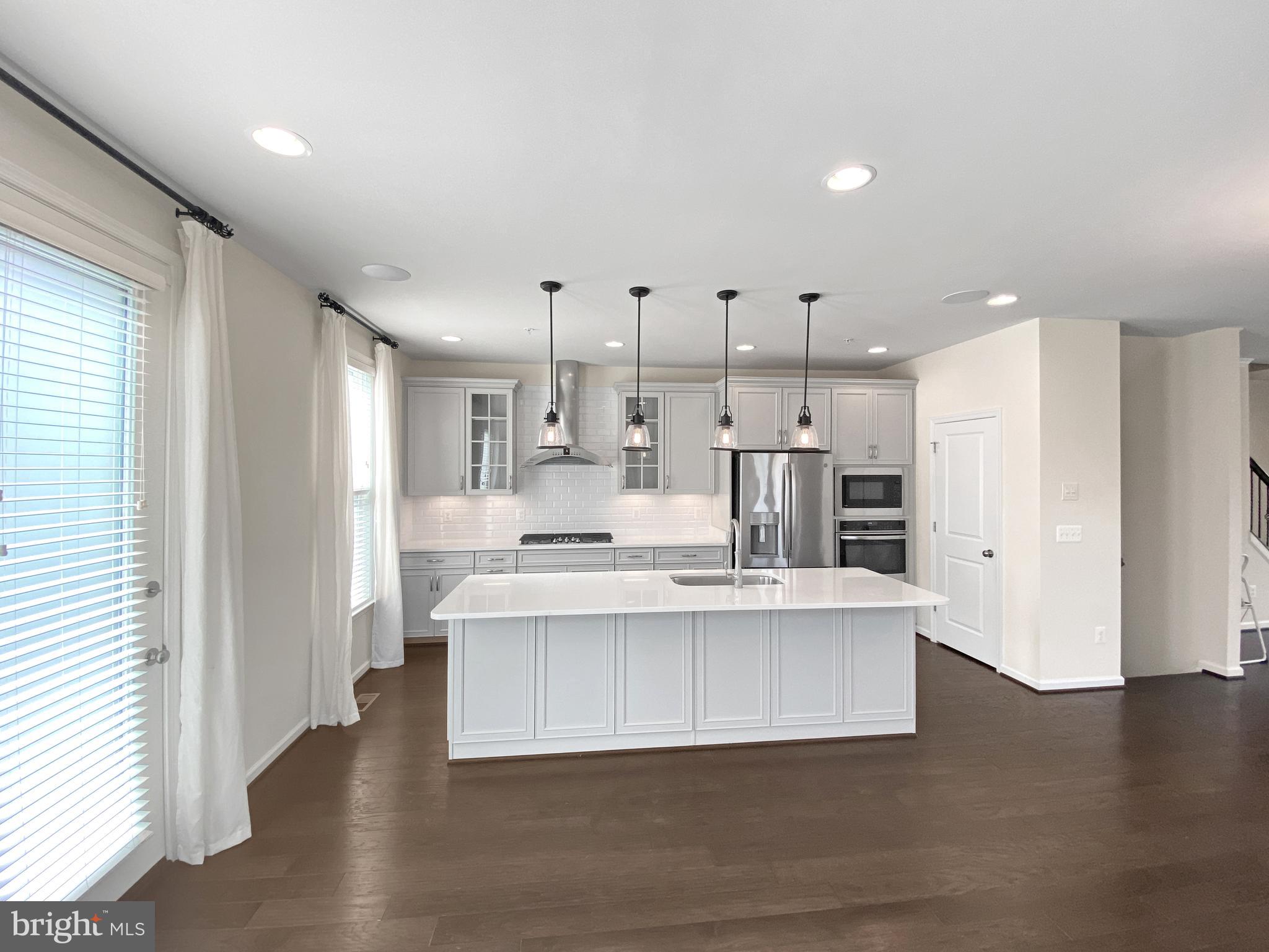 4967 Lakeside Crossing Chantilly, VA 20151 - Photo 15 of 45 a large white kitchen with kitchen island a sink a stove a refrigerator and a window