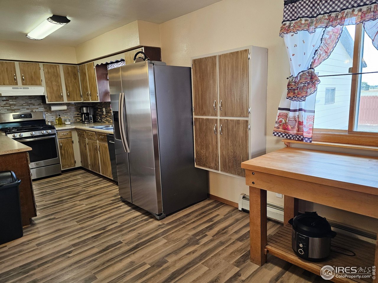 570 California Street Sterling, CO 80751 - Photo 10 of 41 a kitchen with kitchen island a wooden floor and a refrigerator