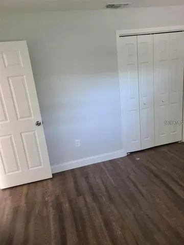 an empty room with wooden floor and closet