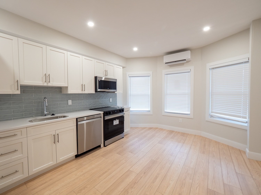 a large kitchen with granite countertop a stove top oven a sink and dishwasher with wooden floor