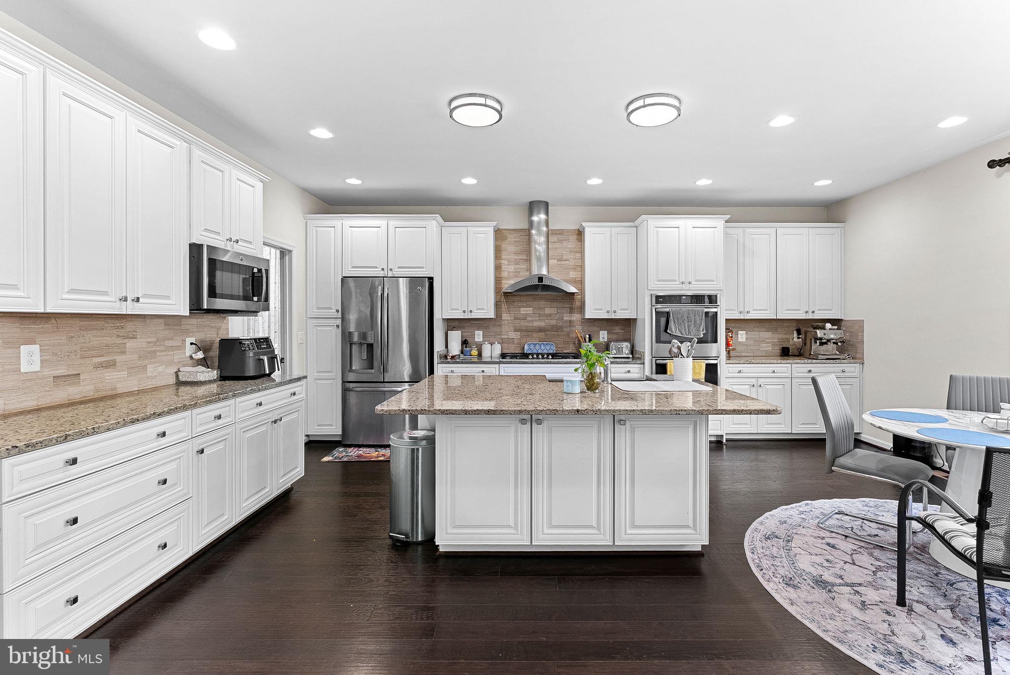 1010 Themis Street Southeast Leesburg, VA 20175 - Photo 21 of 64 a kitchen with stainless steel appliances kitchen island granite countertop a stove top oven a refrigerator a sink and white cabinets with wooden floor