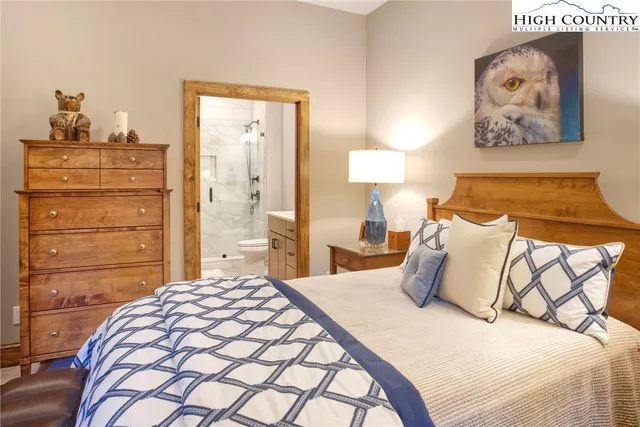 a bedroom with a bed and a lamp on dresser