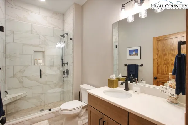 a bathroom with a sink a toilet a mirror and shower