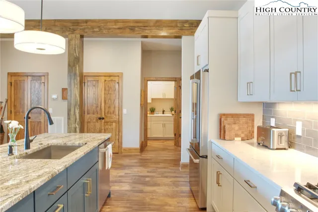 a kitchen with a sink dishwasher a refrigerator and cabinets with wooden floor