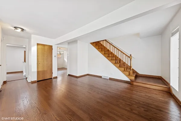a view of an empty room with wooden floor and stairs