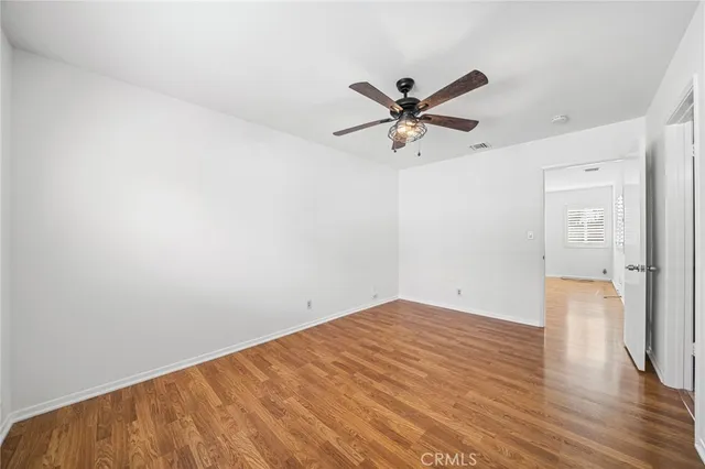 a view of a big room with wooden floor and a chandelier fan