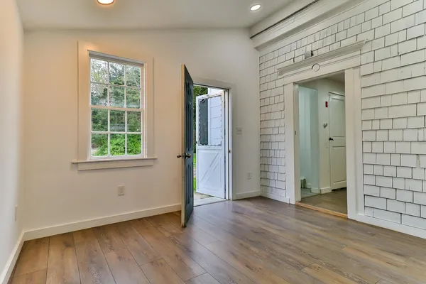 a view of an empty room with wooden floor and a window