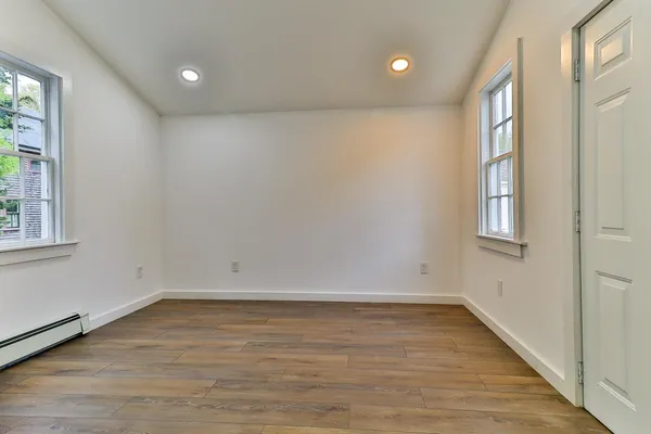 an empty room with wooden floor and windows