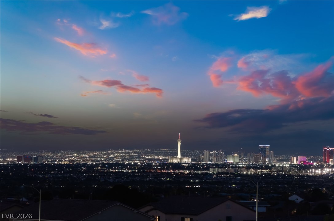 6432 Spring Jog Street Las Vegas, NV 89166 - Photo 54 of 61 Dramatic sunset hues paint the sky over a twinkling cityscape and iconic tower.