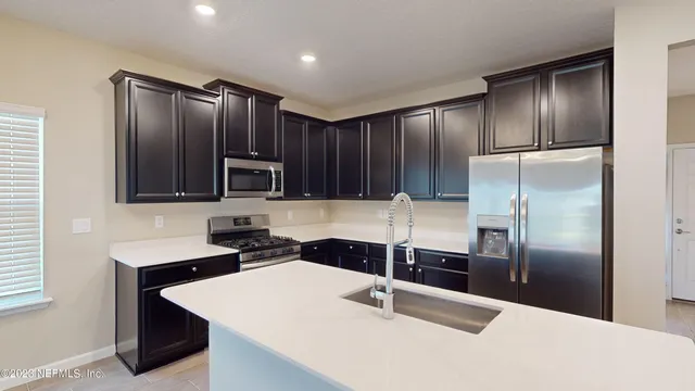 a kitchen with stainless steel appliances kitchen island granite countertop a refrigerator a stove and a sink with wooden floor