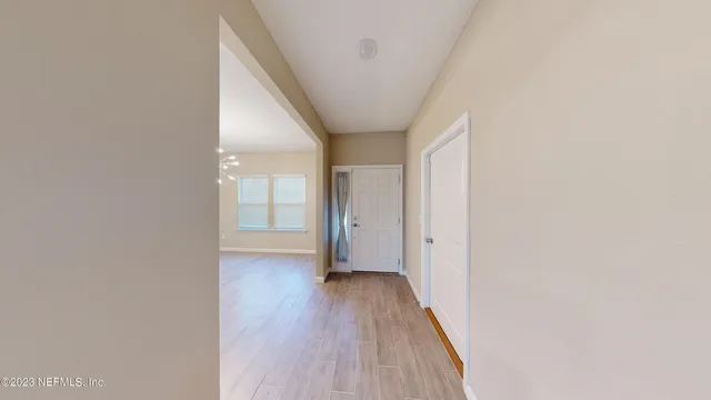 an empty room with chandelier fan and windows