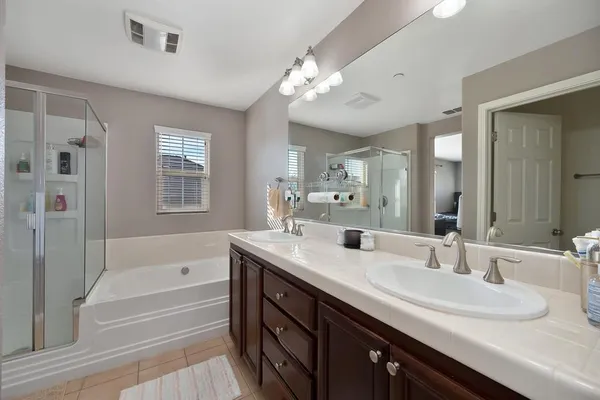 a bathroom with a tub a sink double vanity and a mirror