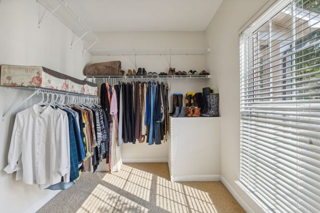 a view of walk in closet with clothes and shoes