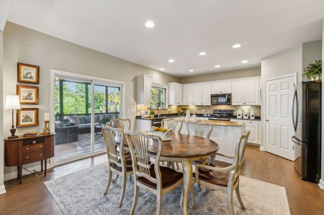 a kitchen with stainless steel appliances kitchen island granite countertop a dining table chairs and refrigerator