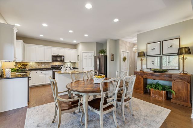 a dining area with stainless steel appliances kitchen island granite countertop a dining table and chairs