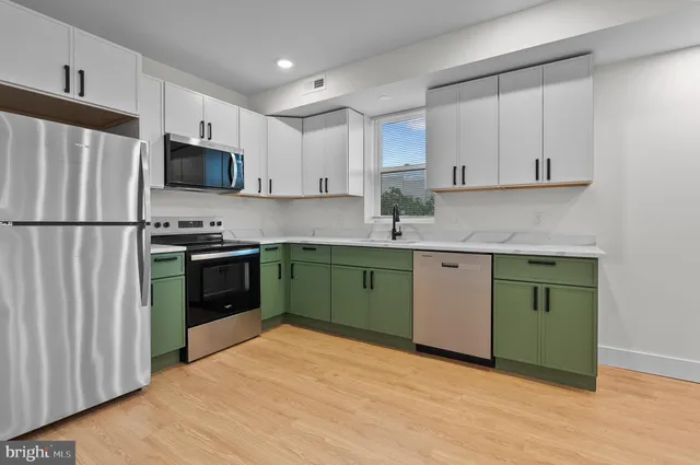 a kitchen with granite countertop a sink stainless steel appliances and white cabinets
