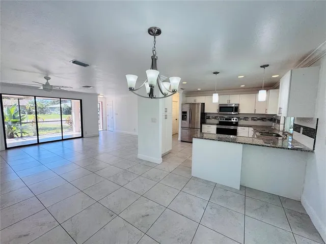 a large kitchen with stainless steel appliances granite countertop a stove a sink a microwave and cabinets