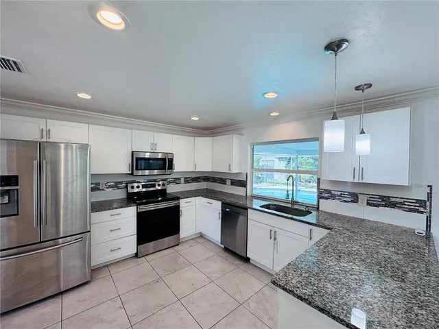 a kitchen with stainless steel appliances granite countertop a stove sink and refrigerator