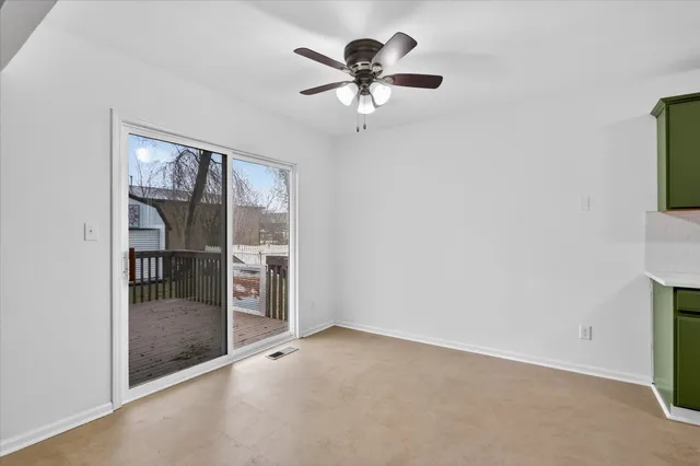 an empty room with chandelier fan and windows