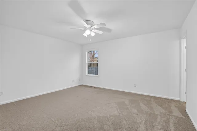 an empty room with a fan & a window